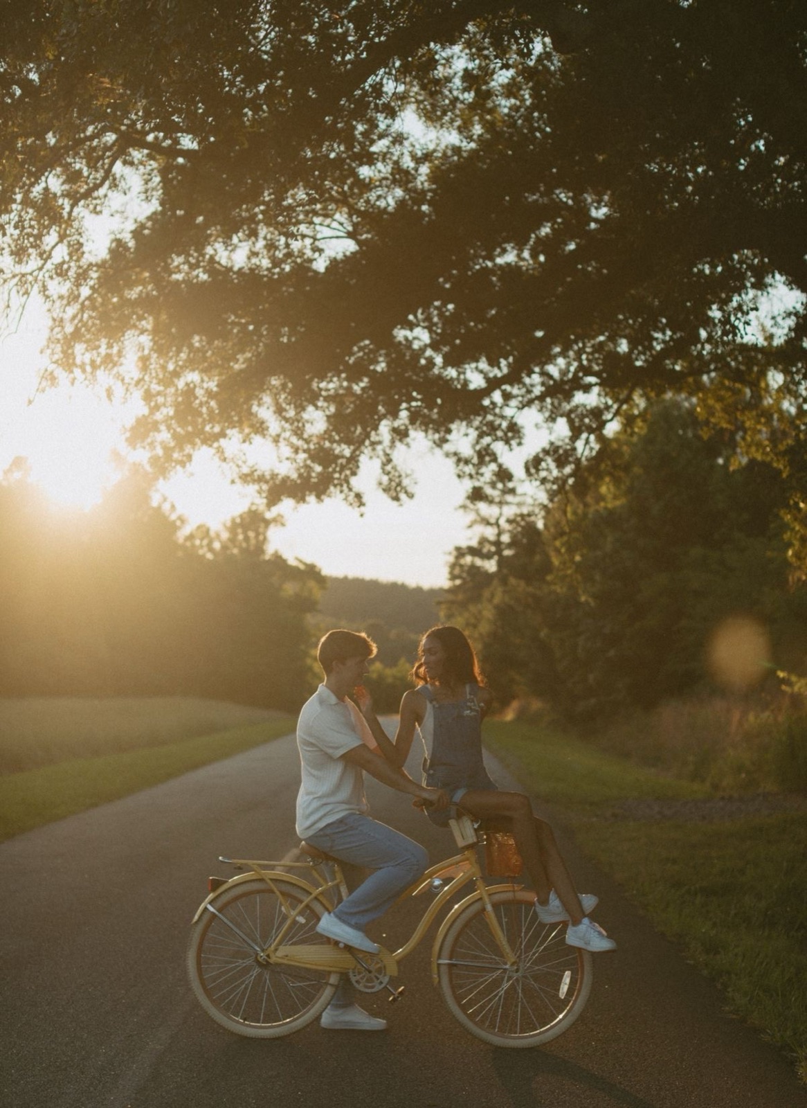 Couple riding bicycles down a country road at sunset