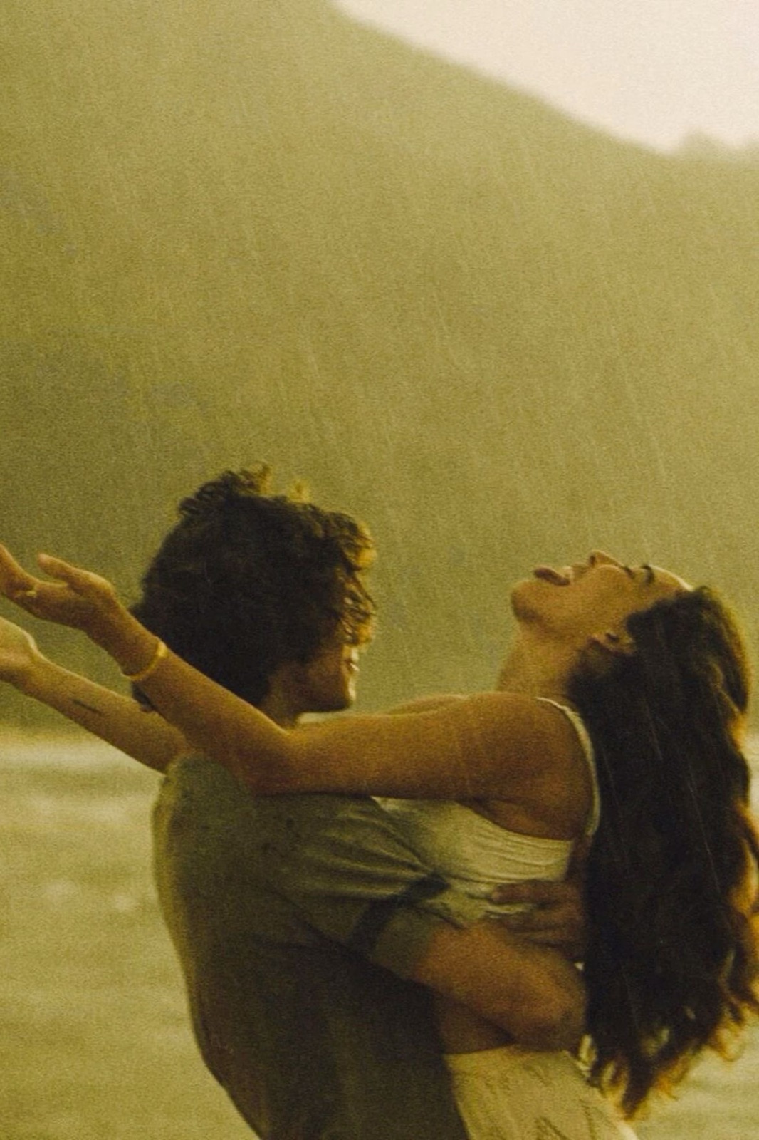 Couple dancing in the rain in front of mountains