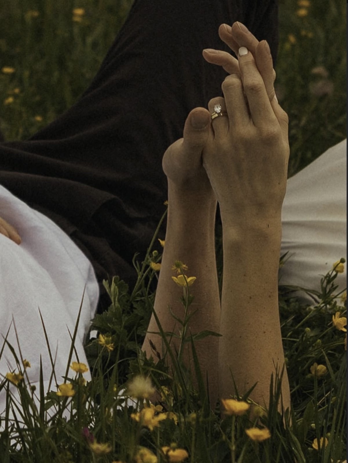 Hands intertwined in a field of wildflowers