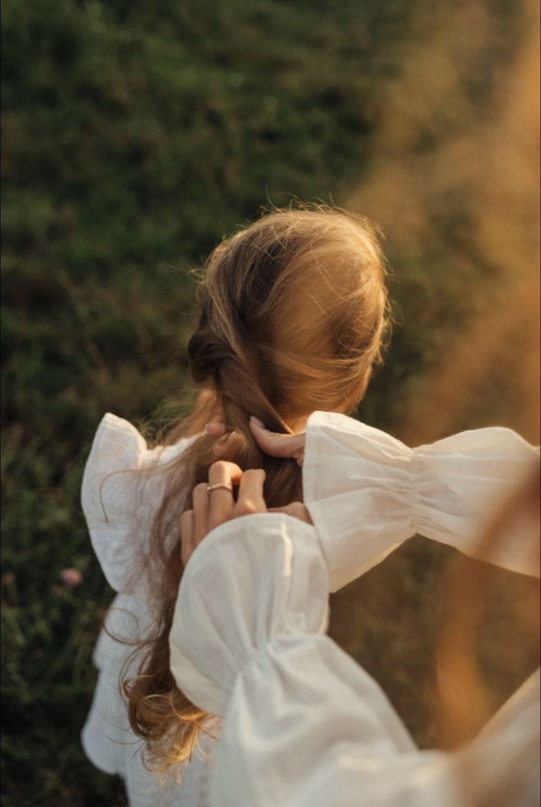 Girl in a white dress walking through a golden field