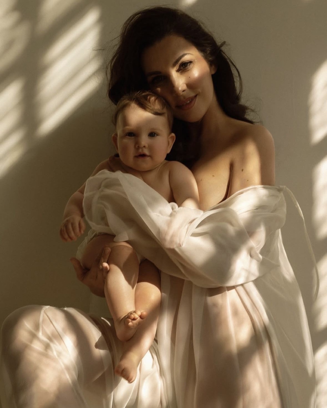 Mother holding her newborn in soft window light