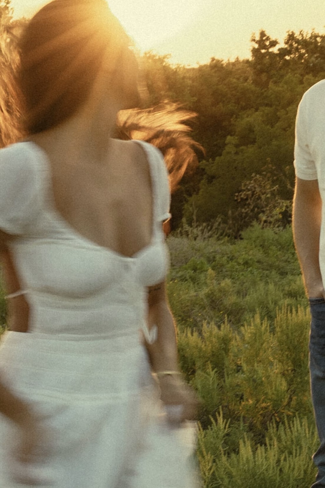 Couple walking through a sunlit field, captured in motion